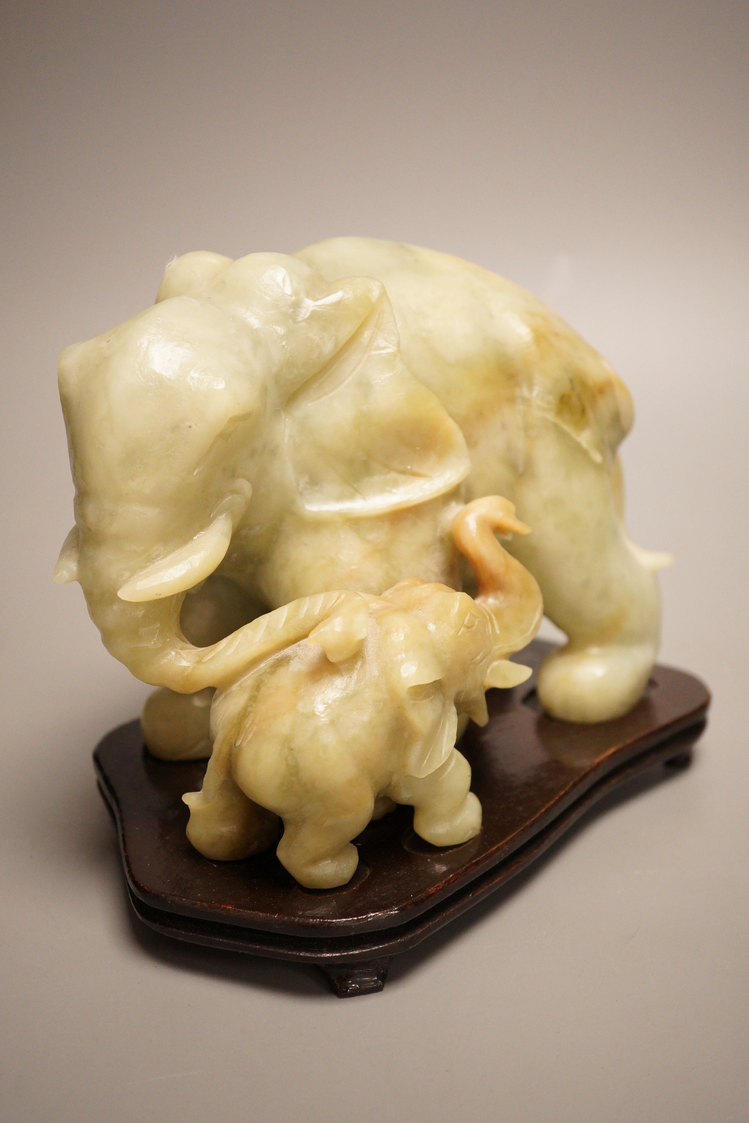 A Chinese carved bowenite ‘elephant’ group on hardwood stand, 15cm